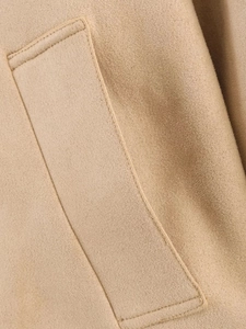 Detail of a camel brown faux suede jacket featuring a stitched pocket and soft texture
