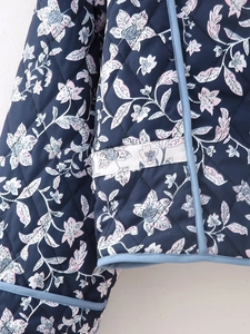 Close-up of diamond quilted reversible jacket featuring dark blue floral pattern and light blue trim