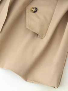 Close-up of khaki trench coat fabric featuring buttoned pocket and twill texture detail