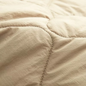 Macro view of light khaki quilted fabric with wavy stitching on women's winter jacket