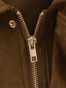 Macro shot of gold metal zipper and textured brown corduroy fabric on a bomber jacket