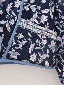 Detail of floral printed quilted jacket with blue binding and diamond stitching texture