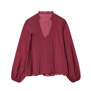 Detail of burgundy V-neck chiffon blouse featuring ruffle trim and pleated fabric texture