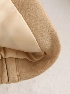 Macro detail of beige knit jacket cuff showing fine texture and smooth inner lining
