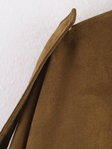 Detailed macro view of brown faux suede fabric with precise stitching and gold metal button