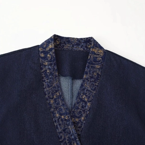 Close-up of vintage gold embroidery on dark blue denim kimono style jacket collar