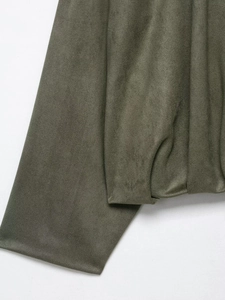 Détail rapproché de la texture en daim vert olive d'une veste aviateur à revers