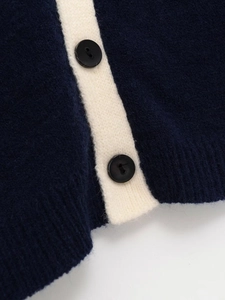 Detailed macro view of navy knit cardigan with cream contrast trim and round black buttons