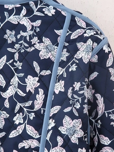 Macro view of quilted fabric featuring navy floral patterns and blue stitched trim