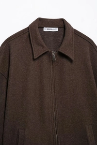 Detail of dark brown wool jacket featuring silver zipper, wide collar, and fabric texture