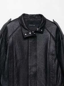 Détail d'un blouson aviateur en cuir noir vintage montrant le grain de peau et les épaulettes