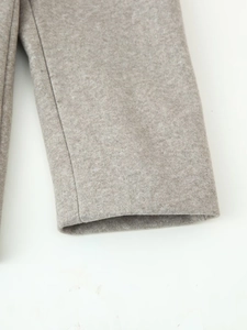 Close-up detail of grey wool blend fabric showing thick texture and fine stitching on the cuff