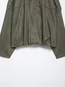 Détail de la veste aviateur en daim vert olive montrant la texture mate du tissu premium