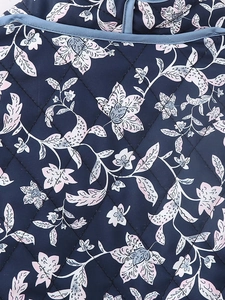 Detail of floral printed fabric with diamond quilting and navy piping on the jacket