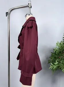 Detail of burgundy trench coat featuring wide lapels, epaulettes, and matching waist belt