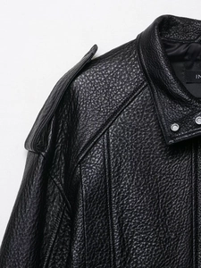 Vue macro de la texture cuir noir avec bouton pression argenté et détail d'épaulette