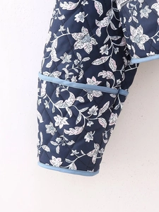 Close-up of quilted floral jacket featuring contrast piping and intricate stitching detail