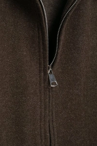 Detail of dark brown wool jacket featuring high-quality fabric texture and silver metal zipper