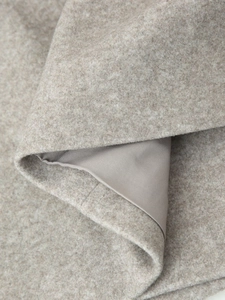 Detailed macro view of high-quality oatmeal wool coat fabric with smooth satin lining