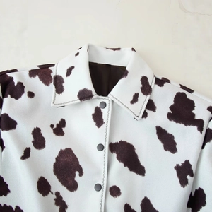 Damen Wolljacke mit Kuhmuster, Reverskragen und schwarzen Knöpfen auf Marmorhintergrund