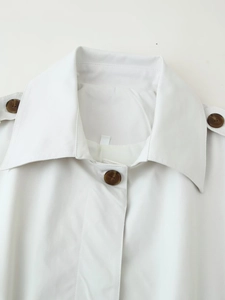 Close-up of white trench coat collar with epaulets and tortoise shell buttons