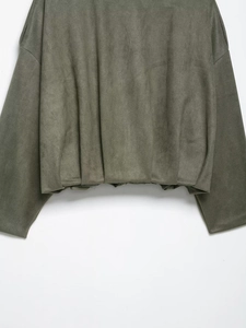 Détail macro du tissu en suédine vert militaire sur une veste aviateur ample