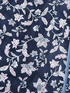 Detail of diamond quilted fabric with navy blue floral print and neat edge binding