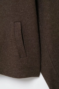 Close-up detail of pocket and textured wool fabric on brown oversized jacket