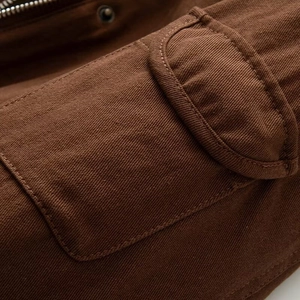 Detailed macro view of dark brown jacket showing heavy twill fabric and flap pocket