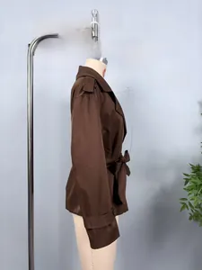 Side view of dark brown short trench jacket featuring lapels and belted waist detail