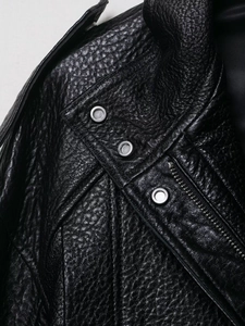 Gros plan sur la texture grainée et les boutons en métal d'un blouson aviateur noir en cuir