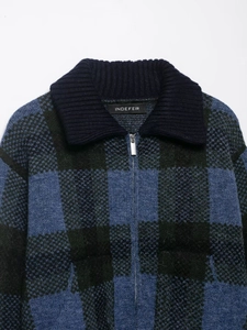 Dettaglio del cardigan in maglia a scacchi blu e verdi con zip e colletto a costine