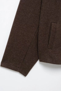 Detail of dark brown wool coat showing sleeve stitching and side slit pocket design