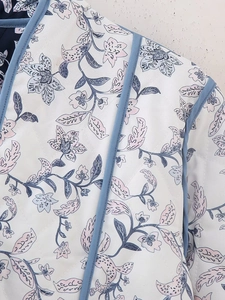 Detailed close-up of quilted floral fabric with diamond stitching and blue piping trim