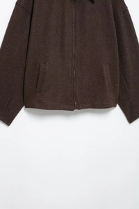 Close-up of dark brown wool jacket featuring textured fabric and silver front zipper