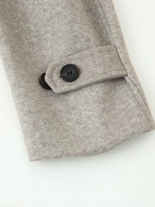 Detailed close-up of grey wool coat cuffs with adjustable button straps and soft texture