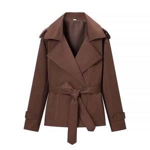 Detail of a brown cropped trench coat featuring wide lapels, belt, and shoulder epaulettes