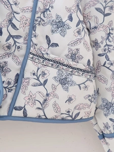 Detail of floral quilted jacket featuring diamond stitching and blue contrast piping