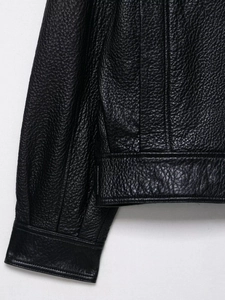 Gros plan détaillé de la texture de cuir litchi noir et coutures de la veste aviateur