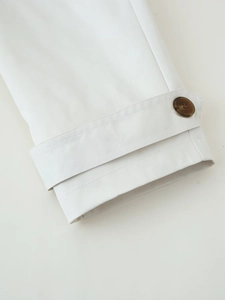 Close-up of beige twill trench coat cuff with adjustable buckle and marble texture button