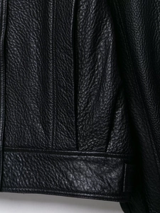 Gros plan de la veste en cuir noir montrant le grain naturel et les coutures soignées