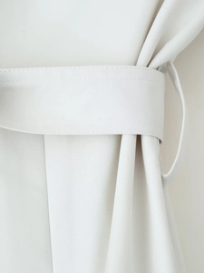 Detail of waist belt loop and twill fabric texture on a beige short trench coat