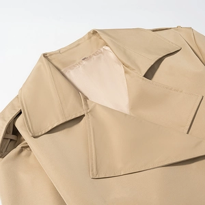 Detailed close-up of khaki trench coat notch lapel with shoulder straps and stitching