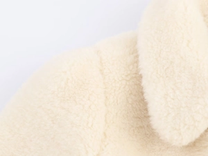 Close-up of white faux fur coat material showing soft curly texture and seam detail