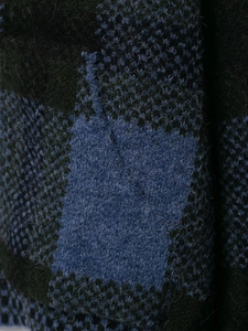 Dettaglio macro del cardigan a quadri che mostra la morbida lana mohair blu scuro