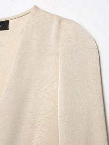 Detail of champagne crinkled fabric texture and V-neckline on a slim fit blouse