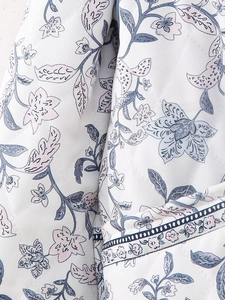 Macro detail of diamond-quilted fabric featuring pastel vintage floral patterns and hem
