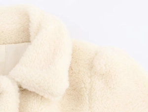 Close-up of cream faux fur texture and collar detail on women coat with belt