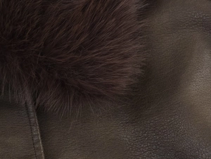 Detail of dark brown faux suede texture and fluffy faux fur collar on winter jacket