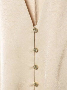 Macro detail of champagne satin shirt with V-neck and embossed gold metal buttons